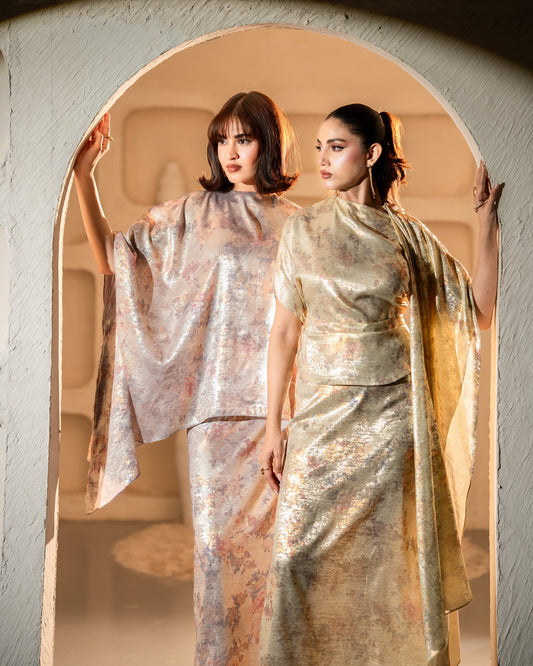Two women in elegant dresses standing in a doorway with a warm glow.
