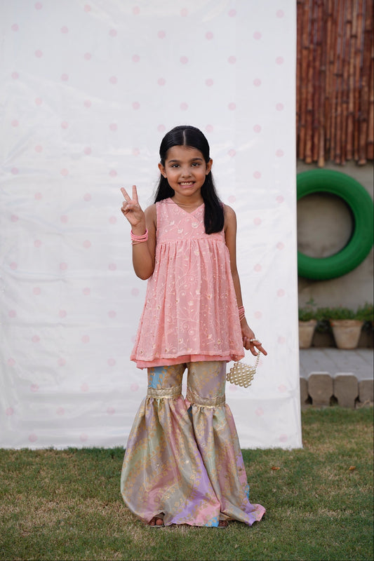 Full front, standing outdoors: "Blush pink embroidered chiffon angrakha top with printed silk gharara, full front view  SHAFAÉ Opal Blush"
