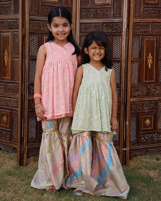 Full front, standing outdoors: "Blush pink embroidered chiffon angrakha top with printed silk gharara, full front view  SHAFAÉ Opal Blush"