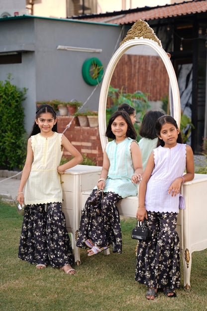 Three young girls in front of a decorative mirror outdoors.