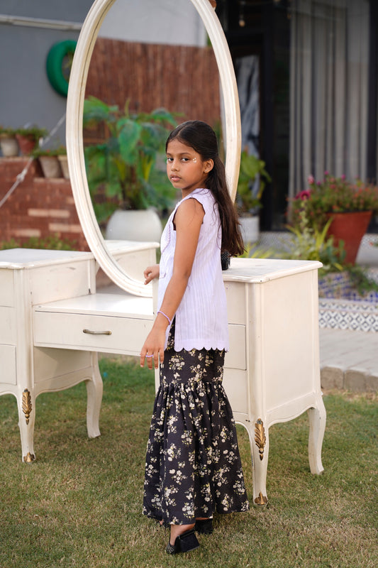 Full front, standing outdoors: "Lemon lawn sleeveless shirt with dark floral printed gharara, full front view SHAFAÉ Lemon Bloom"