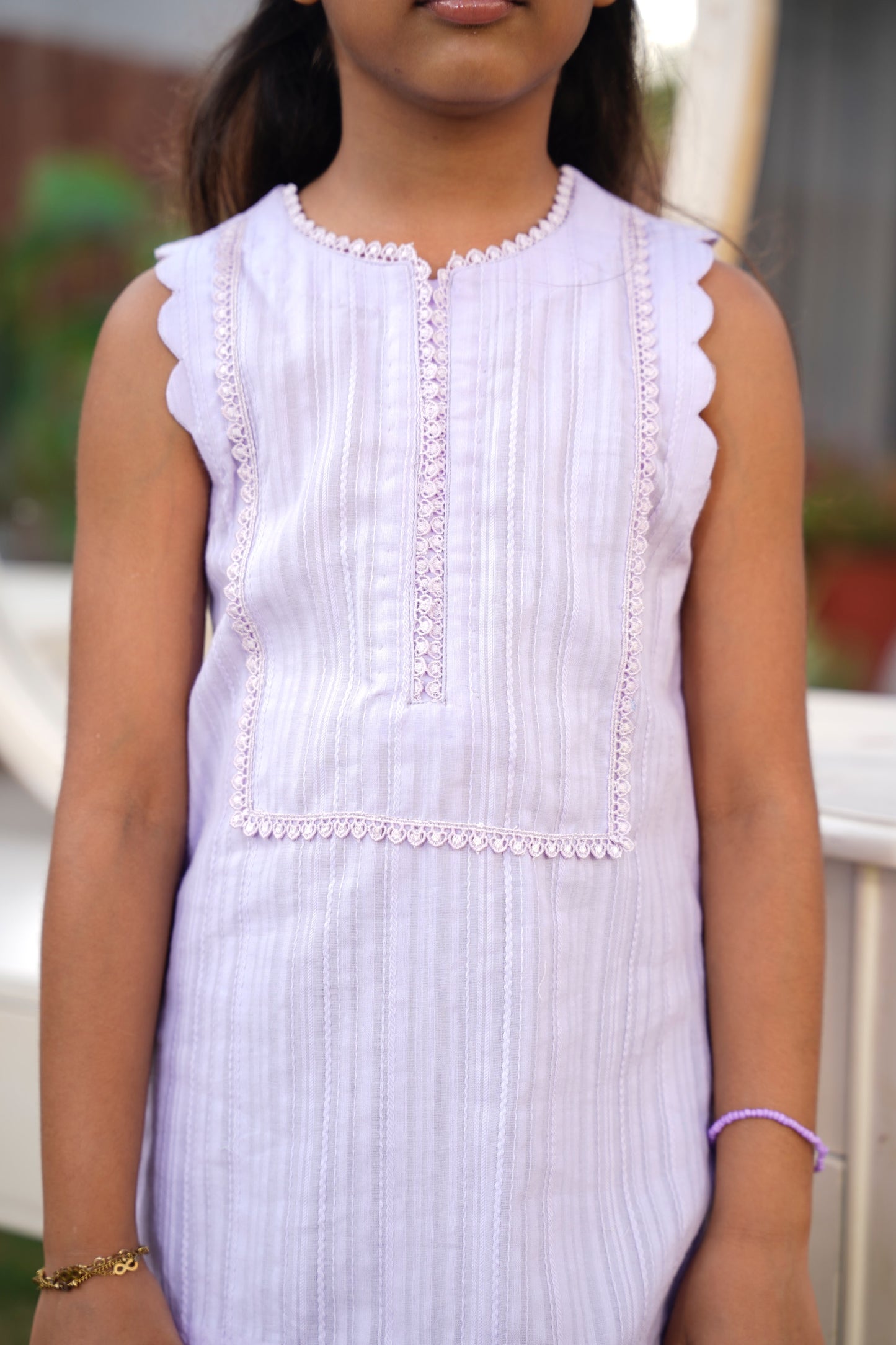 Young girl wearing a white dress with lace details outdoors.