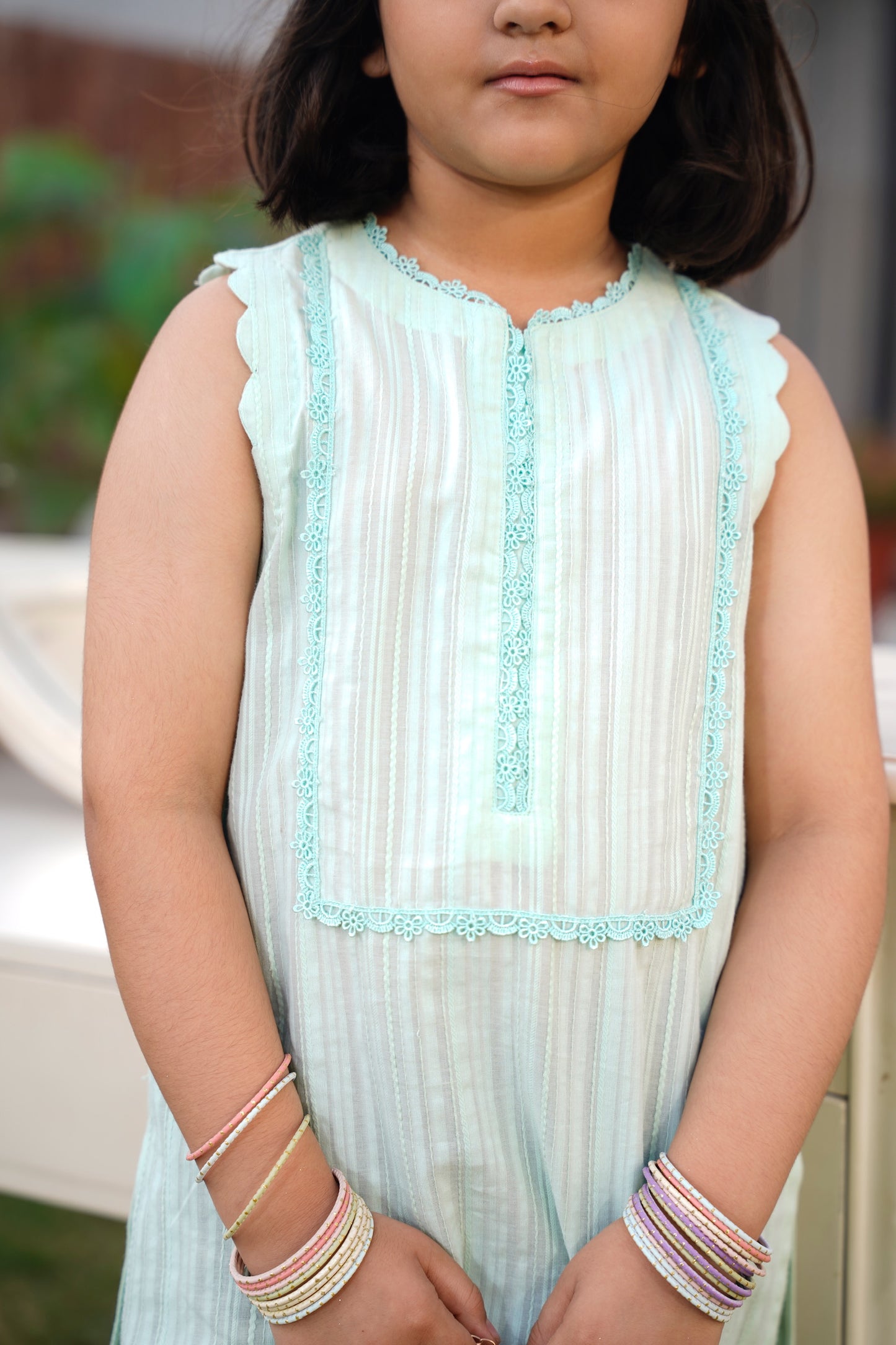 Young girl wearing a light blue sleeveless top with lace trim and pleated design.  full front view — SHAFAÉ Mint Bloom"