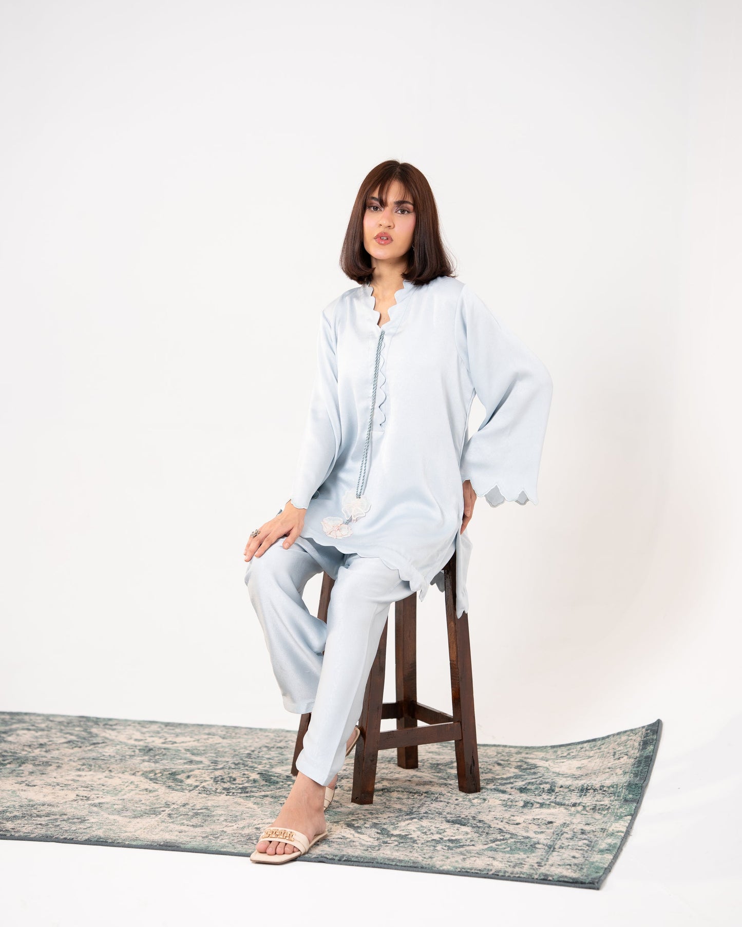 "Woman in light blue outfit sitting on a wooden stool with a white SHAFAÉ Ice Blue Embroidered Co-Ord set"