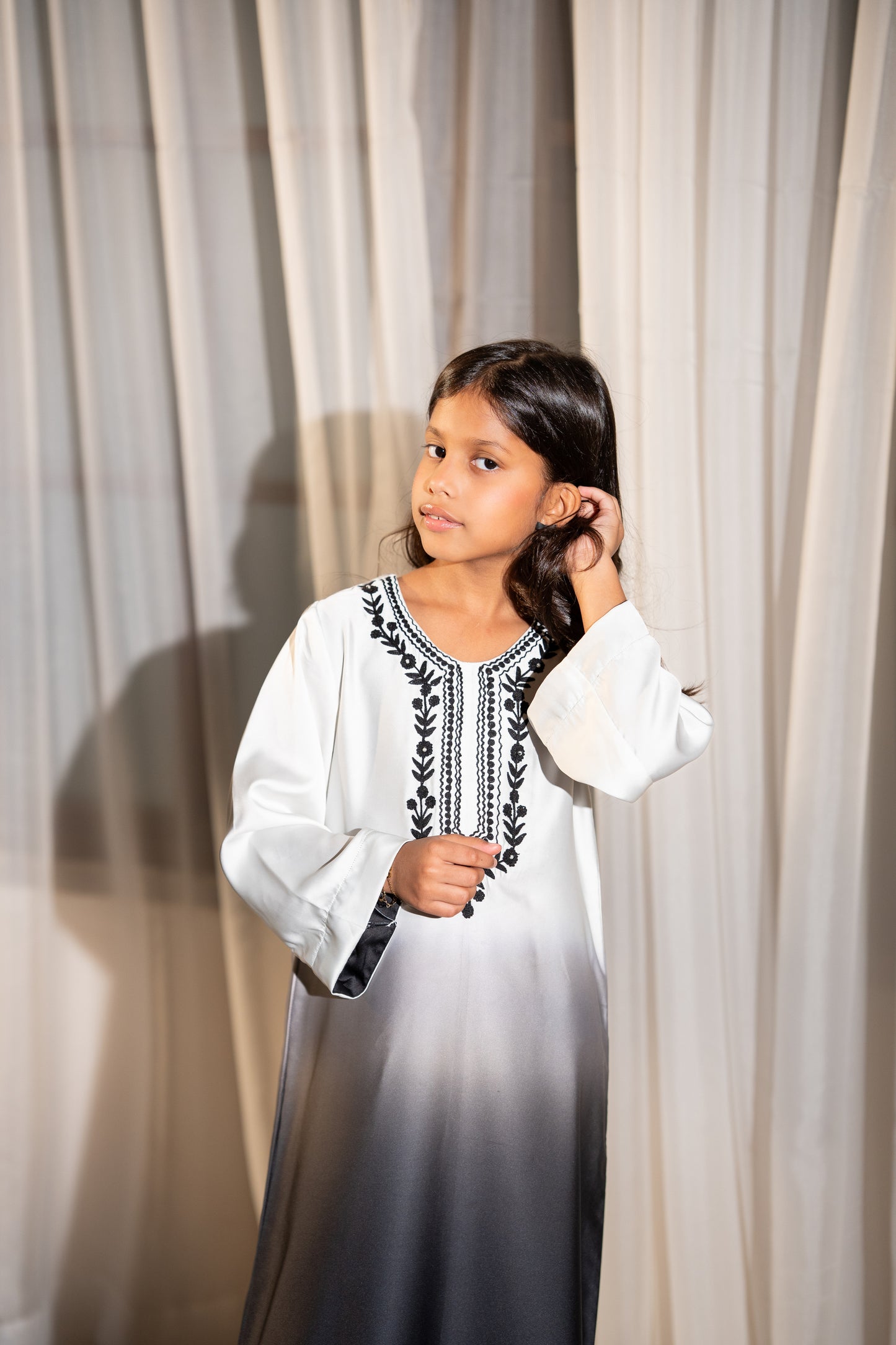 Young girl wearing a ivory dress with black embroidery  ombré silk kaftan fading from ivory to black, side SHAFAÉ Noir Ombre Kaftan"